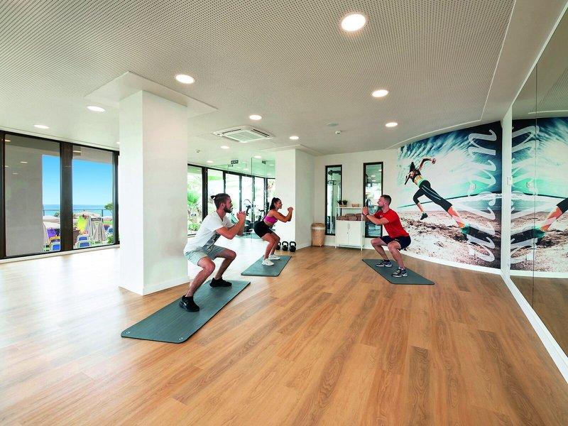 Fitnessraum im Allsun Hotel Sumba mit Personen, die auf Matten trainieren, und einer großen Wandgrafik.