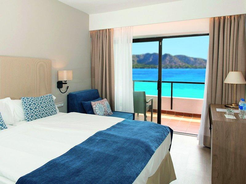 Hotelzimmer mit Meerblick im Allsun Hotel Sumba mit einem Bett, Sofa und Schreibtisch.