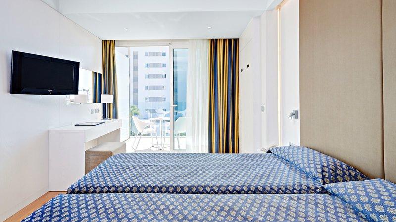 Doppelzimmer im Hipotels Don Juan mit zwei Betten, Fernseher, Schreibtisch und einem Blick auf das Meer.