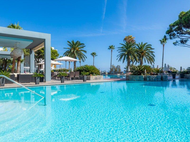 Außenpool des Marins Playa Suites Hotels mit Palmen und Sonnenschirmen.