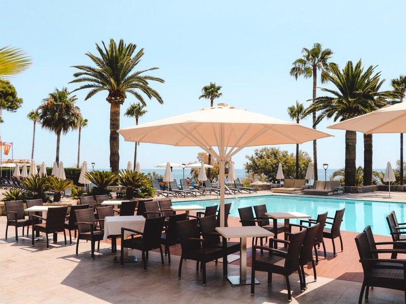 Außenbereich des Marins Playa Suites Hotels mit Pool, Tischen und Sonnenschirmen.
