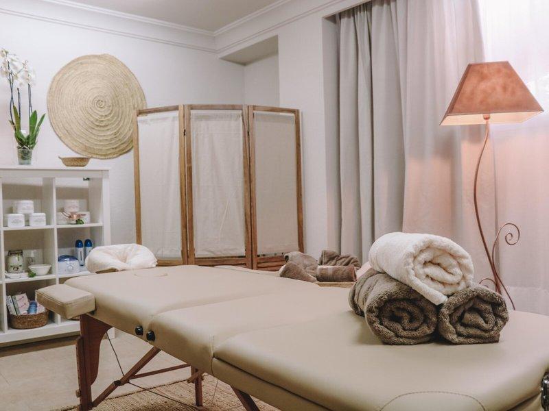 Massageraum im Marins Playa Suites Hotel mit Behandlungsbetten, Handtüchern und einer Lampe.