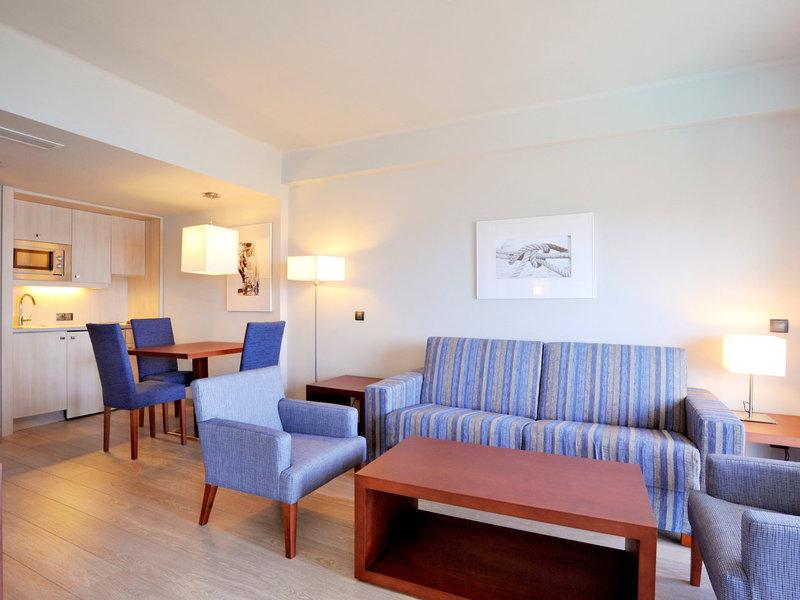 Wohnzimmer der Marins Playa Suites mit blauen Möbeln, einem Sofa, einem Tisch und Stühlen.