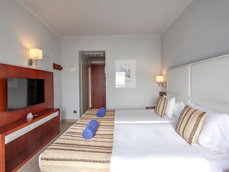 Hotelzimmer von Marins Playa Suites mit zwei Betten, Fernseher und Dekor.
