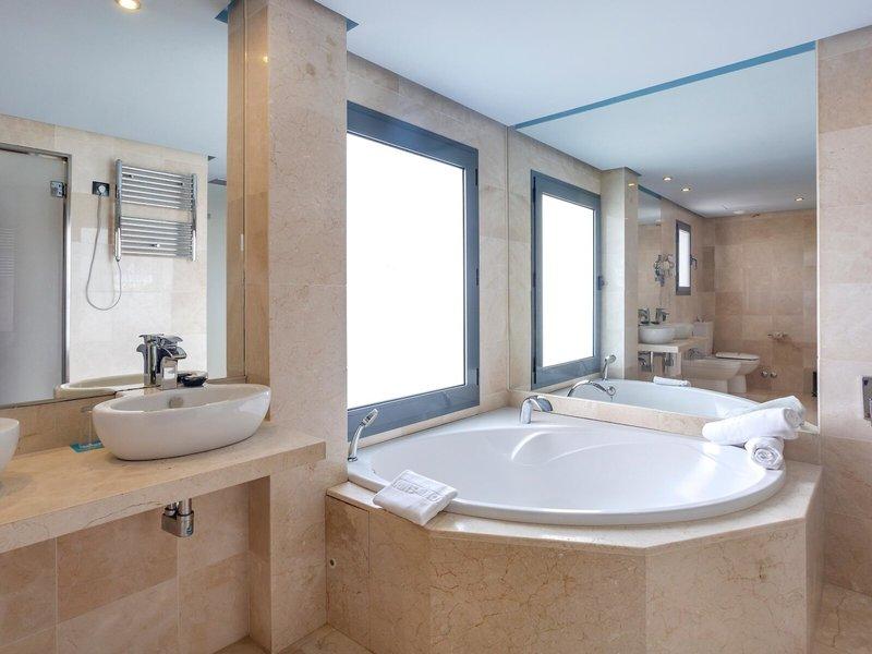 Badezimmer im Marins Playa Suites Hotel mit Badewanne, Spiegel und Waschbecken.