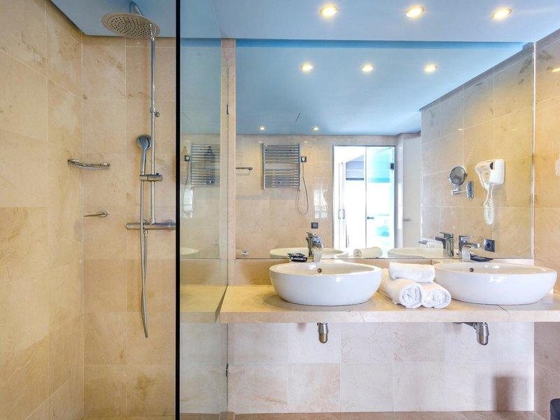 Badezimmer im Marins Playa Suites Hotel mit zwei Waschbecken, Spiegel und Dusche.