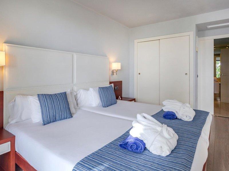 Doppelbett-Zimmer im Marins Playa Suites Hotel mit weißen Wänden und blauen Akzenten.