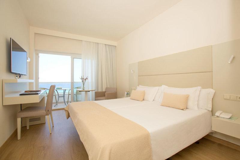 Innenansicht eines Zimmers im Sabina & Suites Hotel mit einem Doppelbett, Schreibtisch und einem Fernseher.