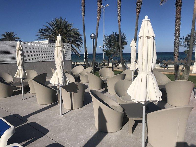 Terrasse des R2 Veronica Beach Hotel mit Stühlen und Sonnenschirmen am Meer