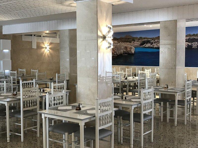 Innenbereich des Restaurants im R2 Veronica Beach Hotel mit weißen Tischen und Stühlen.