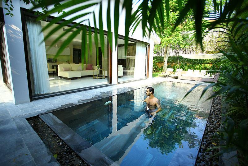 Mann im Pool des TIA Wellness Resorts neben der Terrasse mit Möbeln.
