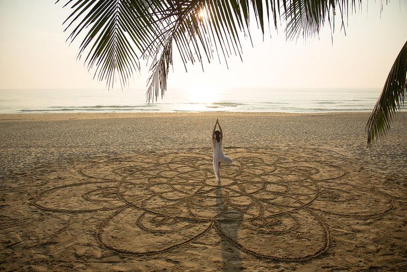Yoga am Strand des TIA Wellness Resorts mit einer Person in einer Lotusposition.