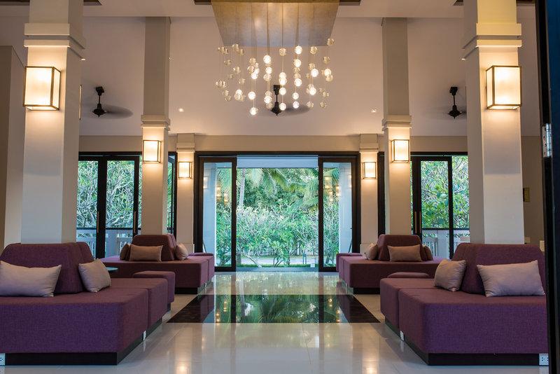 Lobby des TIA Wellness Resorts mit violetten Sofas, Glastüren und großen Fenstern
