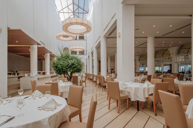 Innenansicht des Restaurants im Lindos Royal Resort mit runden Kronleuchtern und eleganten Esstischen.