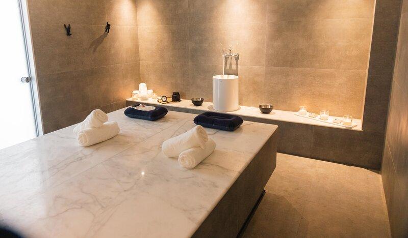 Spa-Behandlungsraum im Lindos Royal Resort mit Marmortisch und blauen Kissen.
