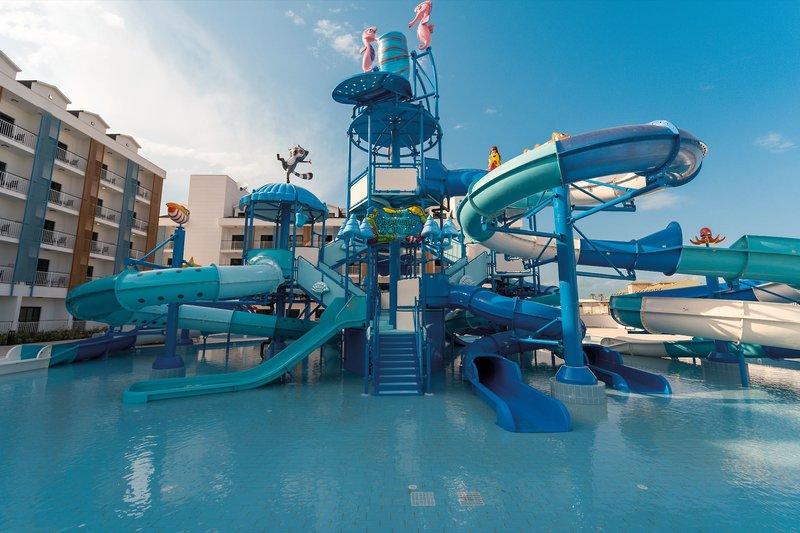 Wasserpark des Arcanus Hotels Trendline in Side mit blauen Rutschen und einem Gebäude im Hintergrund.