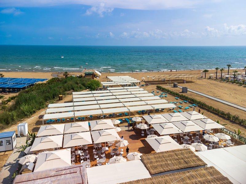 Arcanus Hotels Trendline Side Strandlounge mit weißen Sonnenschirmen und Tischen am Meer