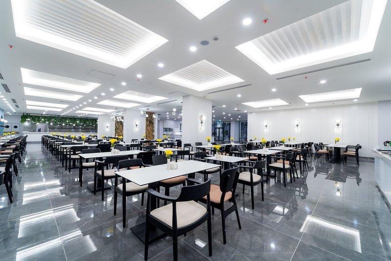 Restaurant im Arcanus Hotels Trendline Side mit weißen Tischen, gelben Blumen und moderner Beleuchtung.