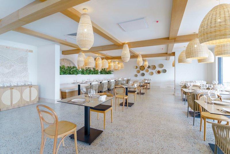 Innenansicht des Restaurants im Arcanus Hotels Trendline Side mit heller Einrichtung, Holzmöbeln und Korblampen.