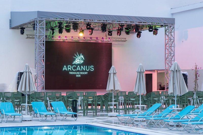 Ein Poolbereich des Arcanus Hotels Trendline Side mit einer Bühne und Loungestühlen.
