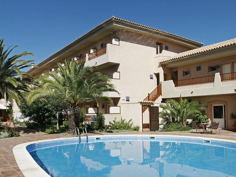 Außenbereich des Voramar Formentera Hotels mit Swimmingpool, Palmen und Terrassen.