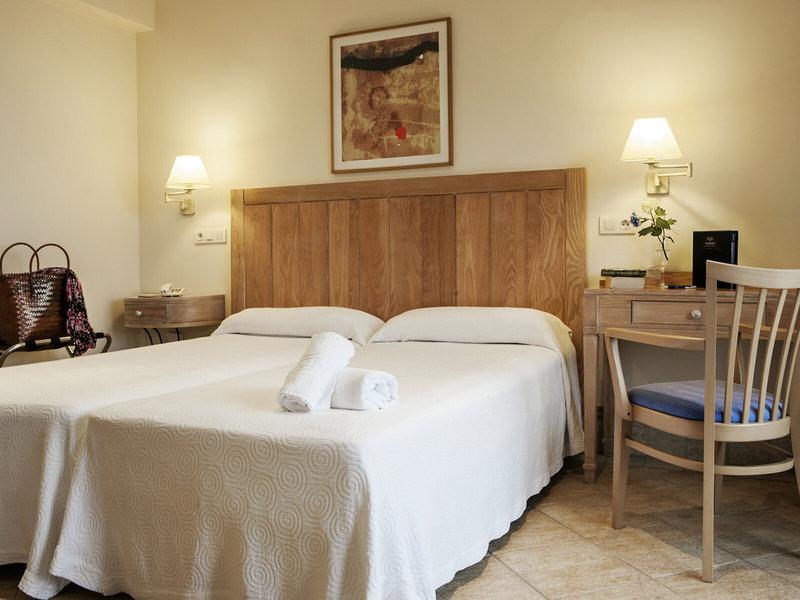 Doppelbett-Zimmer im Hotel Voramar Formentera mit weißem Bettzeug und Holzkopfteil.
