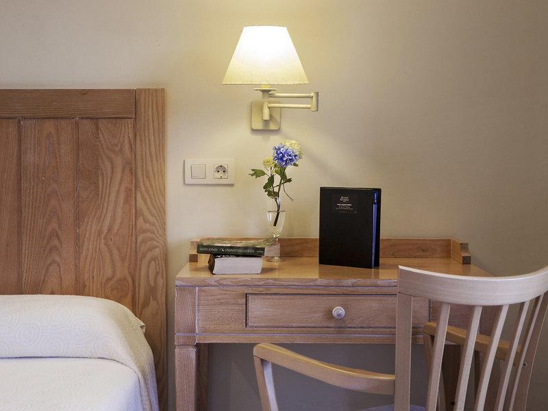 Blick auf den Schreibtischbereich im Voramar Formentera Hotelzimmer mit Lampe, Blumen, Büchern und Nachttisch