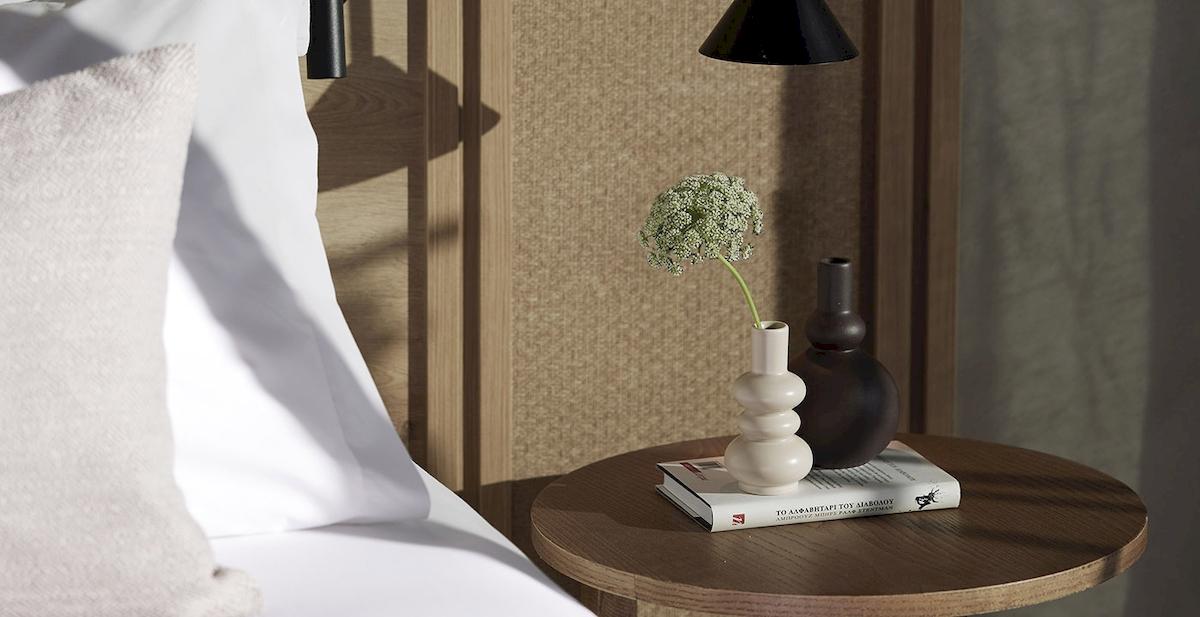 Ein Bett mit Tisch und Blumen im Schlafzimmer, die Nachttischlampe hängt von der Decke.
