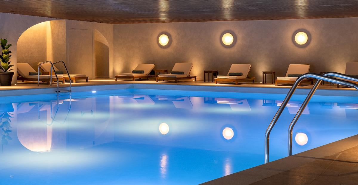 Pool-Loungebereich im Helea Lifestyle Beach Resort mit beleuchteten Wänden und Loungestühlen.