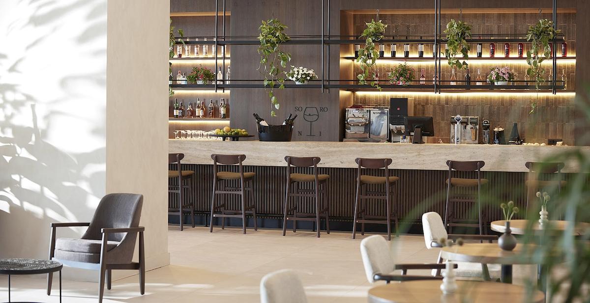 Barbereich im Helea Lifestyle Beach Resort mit gepolsterten Stühlen und Theke.