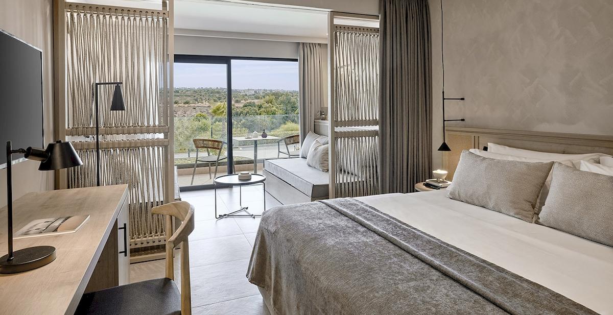 Innenansicht eines Hotelzimmers im Helea Lifestyle Beach Resort mit großem Bett, Schreibtisch und Aussicht.