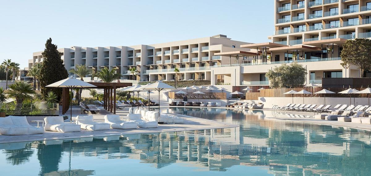 Außenbereich des Helea Lifestyle Beach Resorts mit Pool, Liegen und Sonnenschirmen.