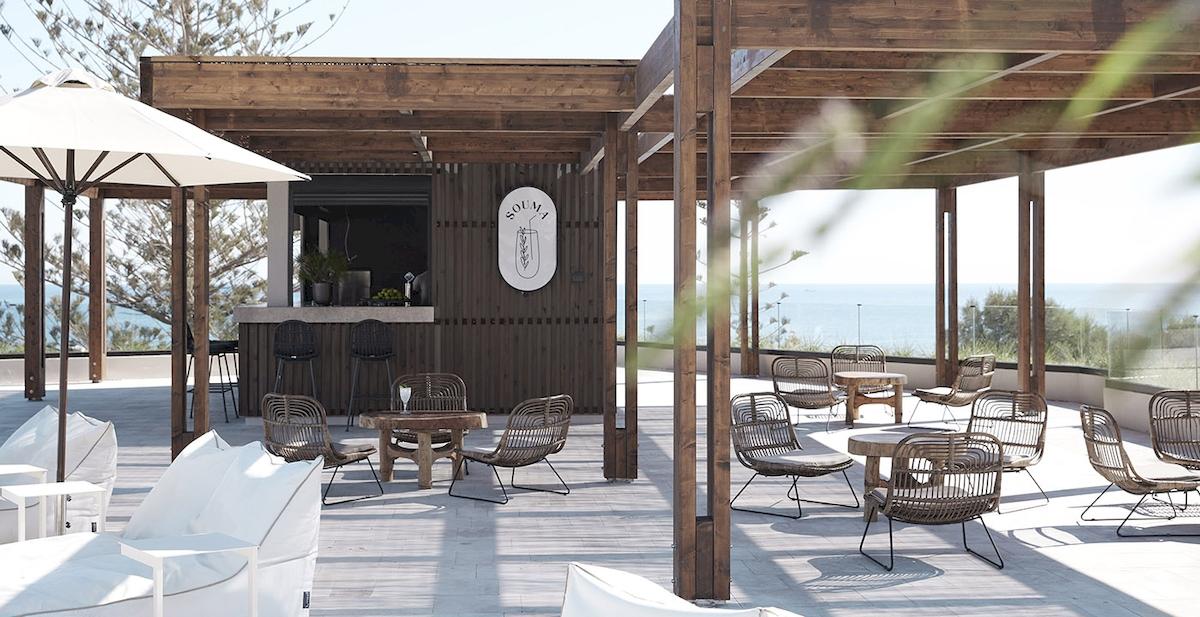 Außenbereich der Helea Lifestyle Beach Resort Bar mit Holzmöbeln und Meerblick.
