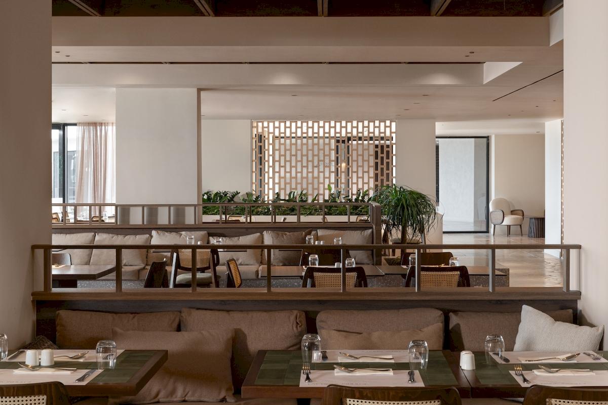 Innenraum des Restaurants im Helea Lifestyle Beach Resort mit Tischen, Stühlen und Pflanzen.