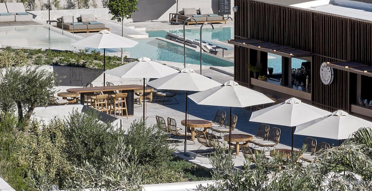 Aussicht auf die Terrasse des Helea Lifestyle Beach Resorts mit Tischen, Stühlen und Sonnenschirmen.