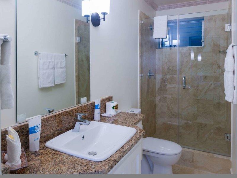 Badezimmer im Rostrevor Hotel mit Waschbecken, Spiegel, Toilette und Glasdusche.