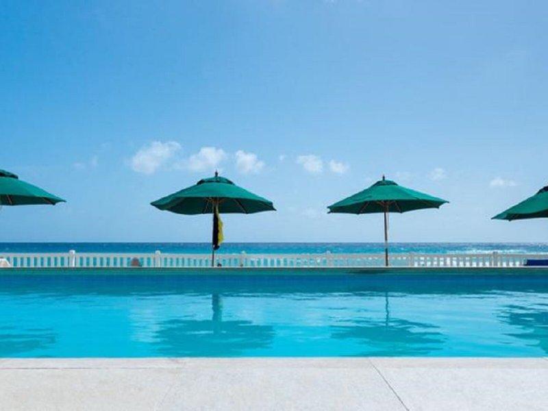 Ein Swimmingpool des Rostrevor Hotels mit grünen Sonnenschirmen und Blick auf das Meer.