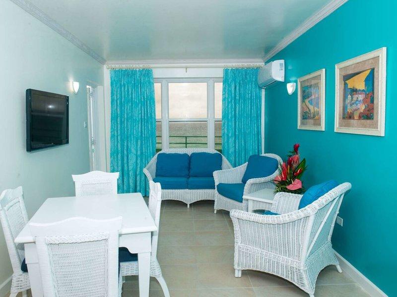 Wohnzimmer im Rostrevor Hotel mit blauen Wänden, weißen Möbeln, einem Fernseher und einem Blick auf das Meer.