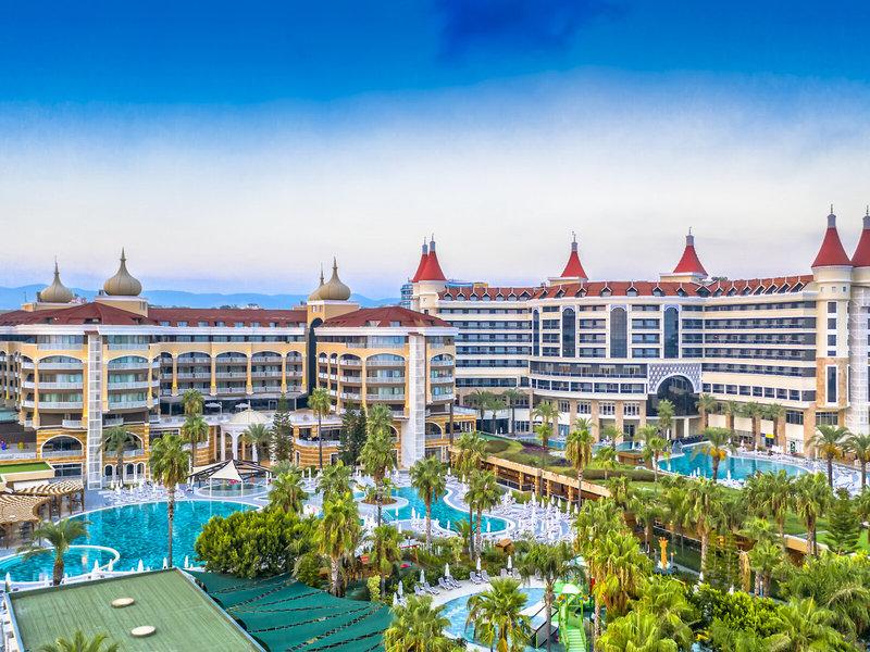 Außenansicht des Kirman Leodikya Resorts mit großen Swimmingpools und Palmen
