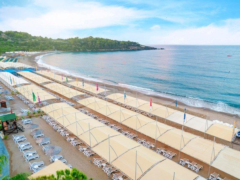 Luftaufnahme des Kirman Leodikya Resorts Strand mit vielen Sonnenliegen und Sonnenschirmen.
