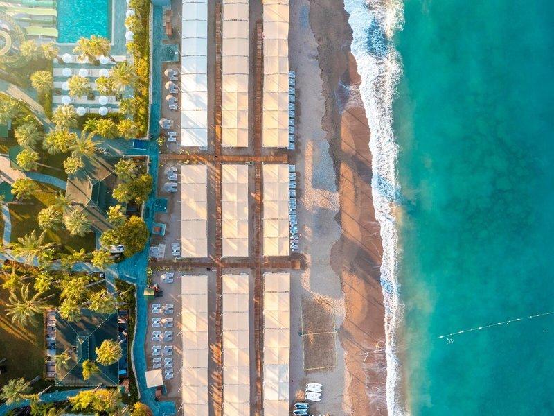 Luftaufnahme des Kirman Leodikya Resorts, Strand mit Sonnenschirmen und Hotelgebäude