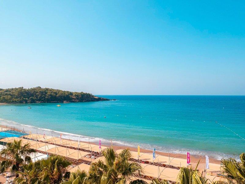 Eine Strandansicht mit dem Kirman Leodikya Resort im Hintergrund.