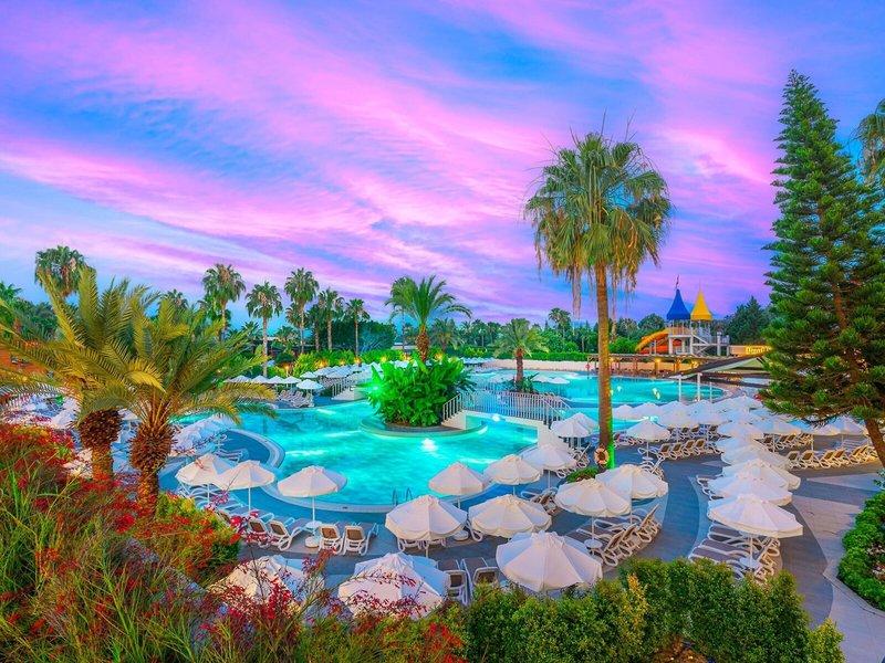 Außenpool des Kirman Leodikya Resorts bei Sonnenuntergang mit buntem Himmel