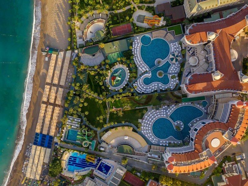 Luftaufnahme des Kirman Leodikya Resorts mit Swimmingpools, Tennisplätzen und einem Amphitheater am Strand
