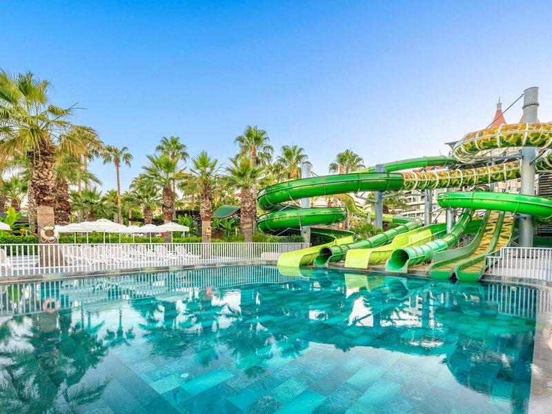 Wasserrutschen im Kirman Leodikya Resort mit einem großen Pool und Liegestühlen.