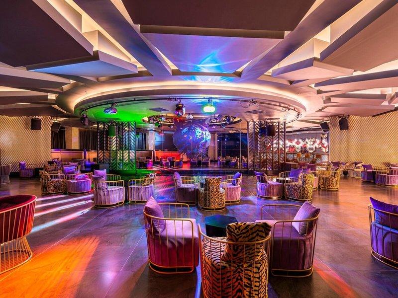 Loungebereich im Kirman Leodikya Resort mit bunten Lichtern und gepolsterten Stühlen.