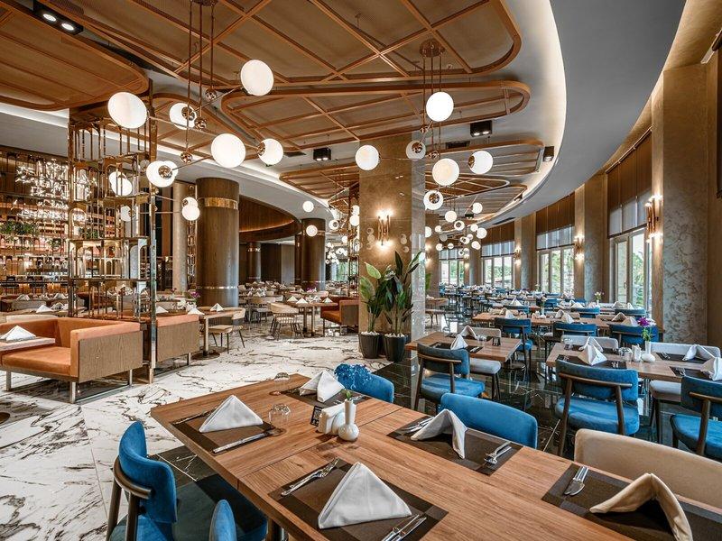 Innenbereich des Restaurants im Kirman Leodikya Resort mit eleganten Tischdecken und modernen Möbeln.