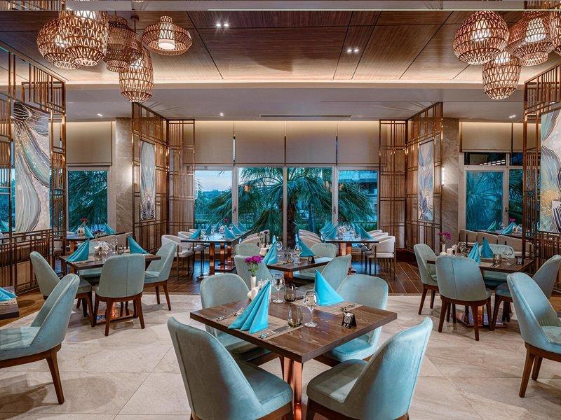 Innenansicht des Restaurants im Kirman Leodikya Resort mit blauen Stühlen und Tischen.