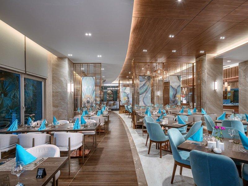 Restaurantbereich im Kirman Leodikya Resort mit modernen Möbeln und blauen Akzenten.