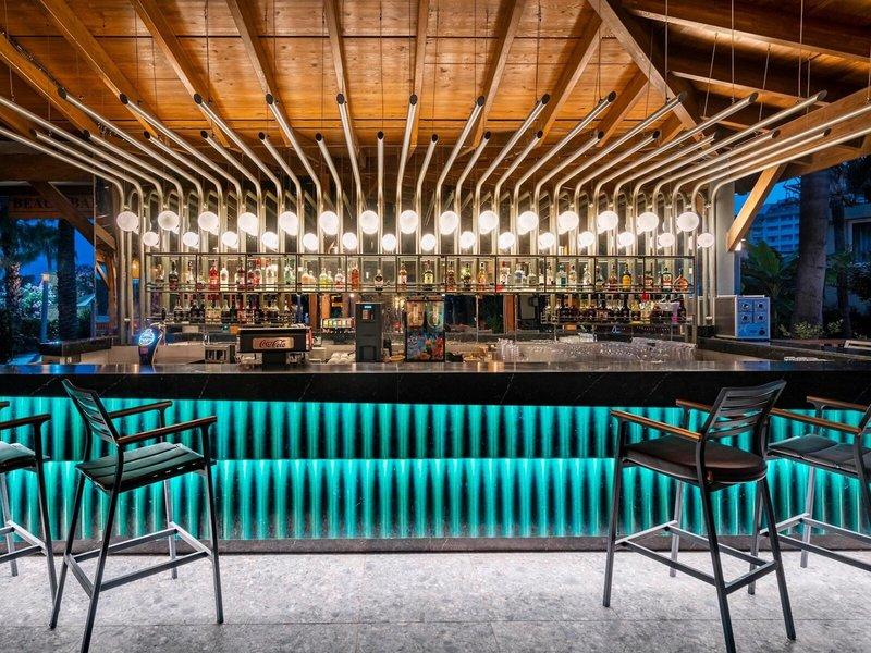 Bar im Kirman Leodikya Resort mit blauen Leuchtleisten und Metallstühlen.